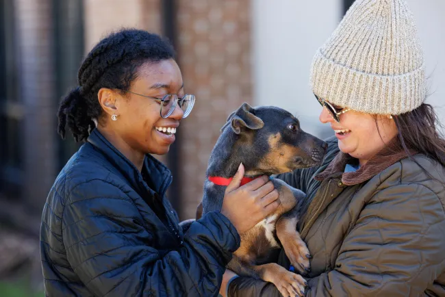 Two shelter volunteers pet and love on a shelter puppy
