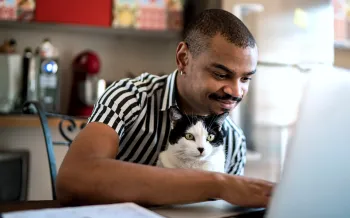A man and his cat look at his laptop