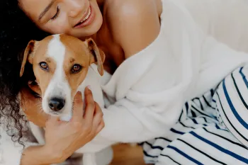 A woman hugs her dog goodbye, but he looks sad and doesn't want her to leave