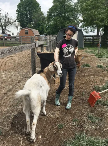 Woman outside with a goat at a farm rescue.