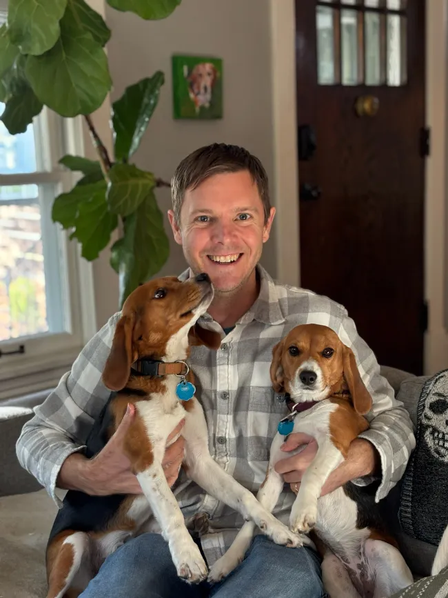 Two beagle puppies rescued from a research laboratory are held by their adoptive father